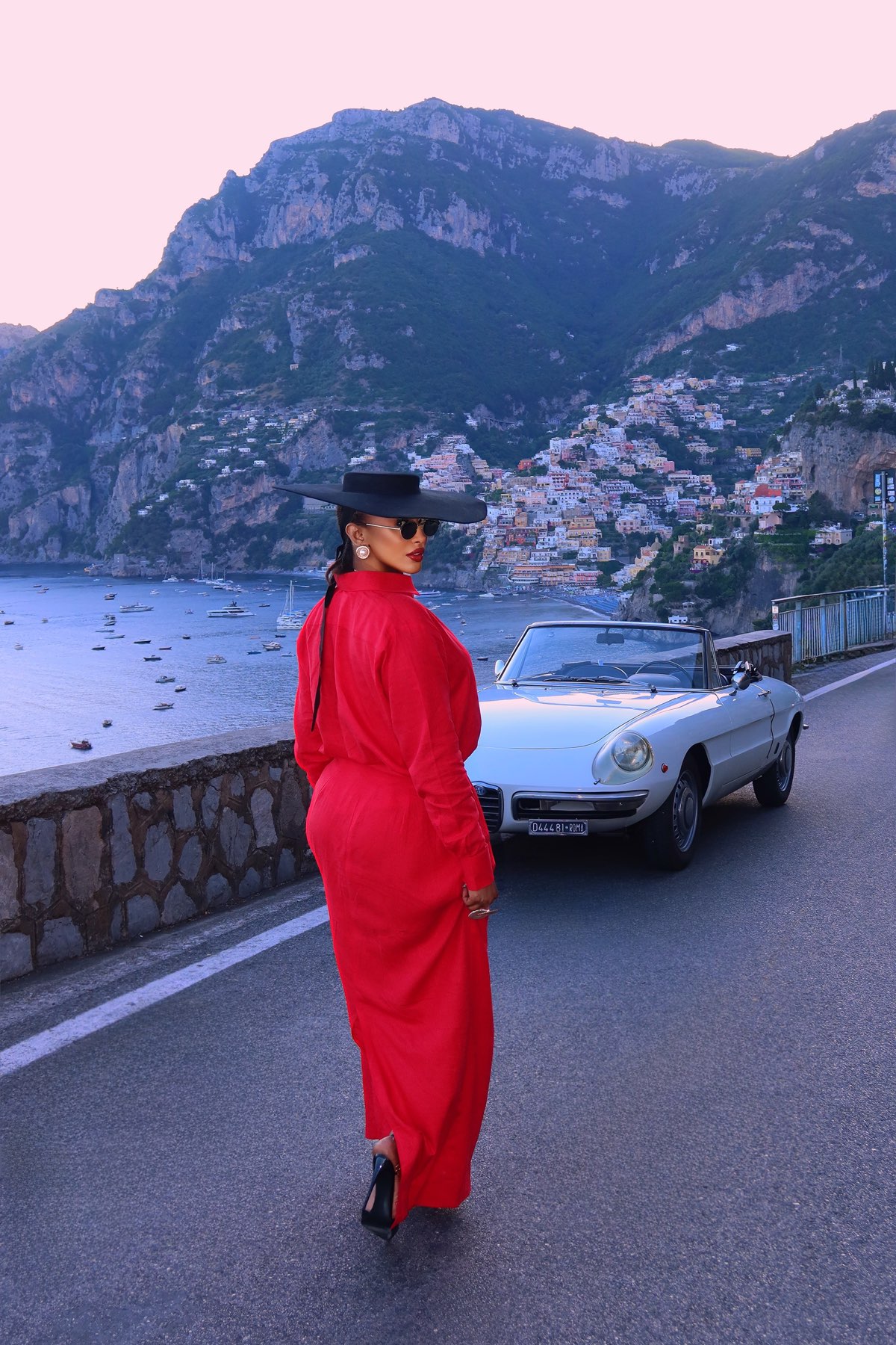 TORYV TRIBE campaign — a floor-length scarlet shirt dress on the Amalfi coast road